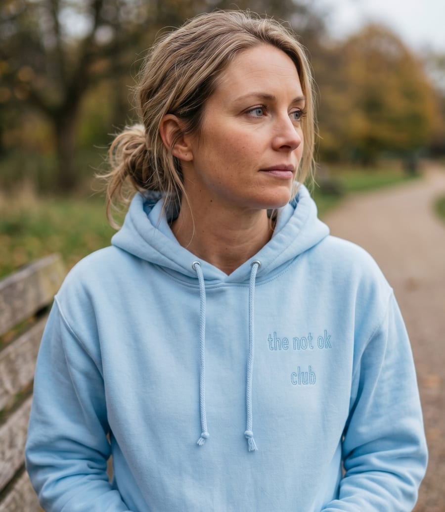 a woman wearing the not ok club light-blue patch hoodie outdoors
